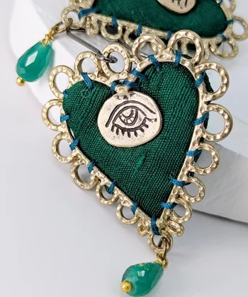 Χειροποίητα σκουλαρίκια σε πράσινο χρώμα με σχήμα καρδιά και κρεμαστό πετράδι. Από ύφασμα και λεπτομέρειες από επιχρυσωμένο ορείχαλκο. Με ασημένιο κούμπωμα 925. Σχεδιάστρια Νεφέλη Καρυοφύλλη.