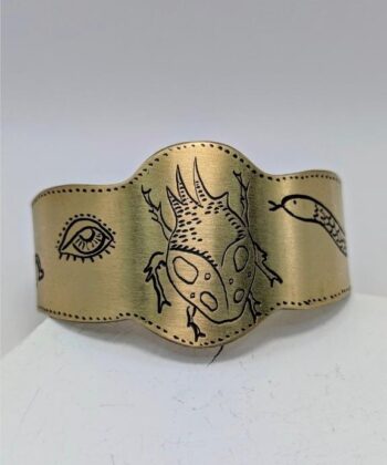 Χειροποίητο βραχιόλι ανοιχτό με σχέδιο σκαραβαίο και χαραγμένα σύμβολα. Από επιχρυσωμένο ορείχαλκο. Σχεδιάστρια Νεφέλη Καρυοφύλλη.